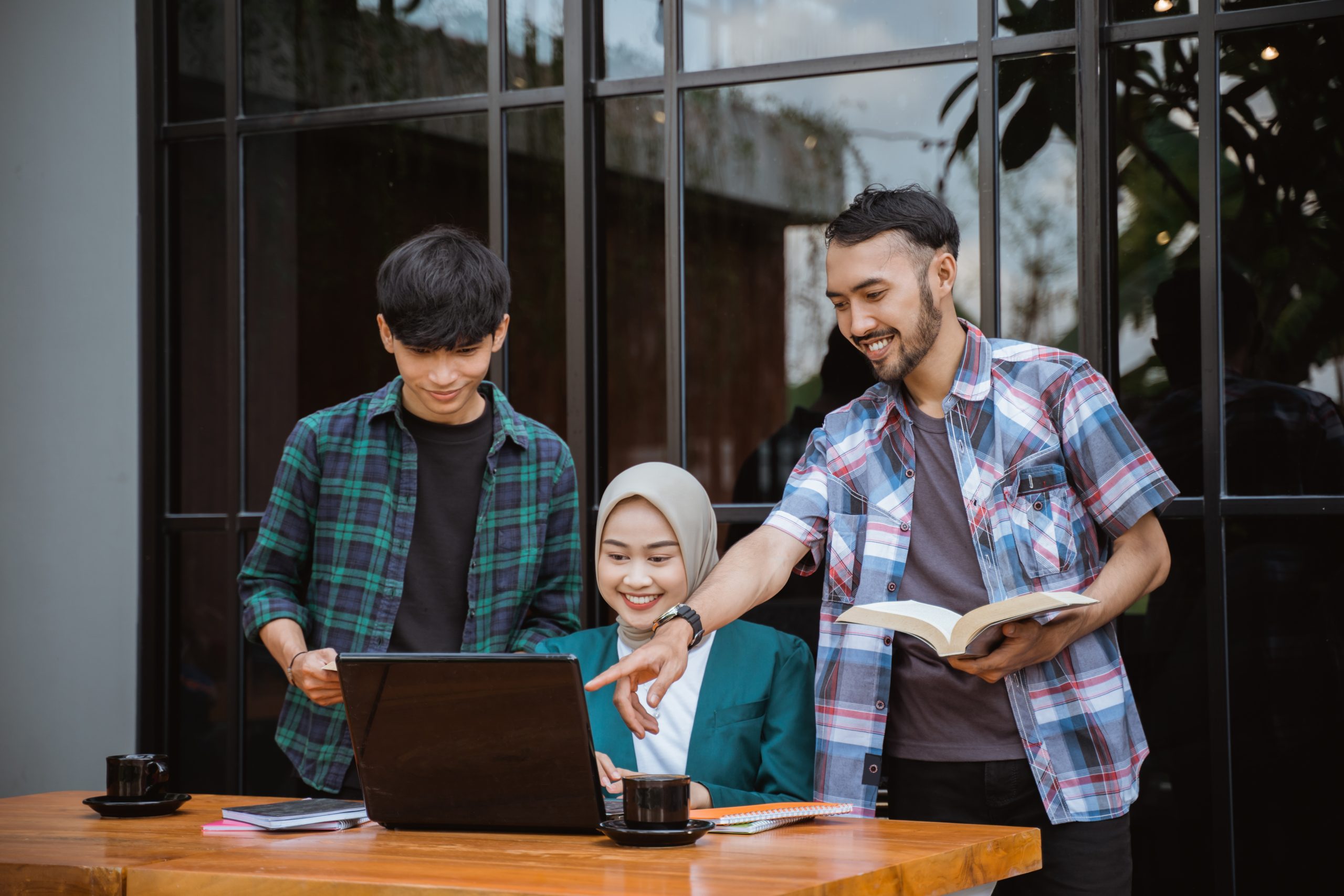two male college students and a female student group work in a cafe